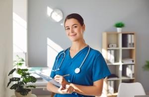 Happy nurse smiling as she writes on a clipboard